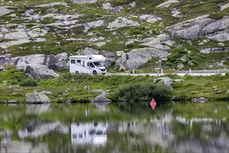 Gotthard Pass, top of the pass. A motorhome is reflected in a mountain lake. Airolo, Canton Ticino,