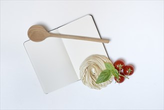 Notebook for recipes, cooking spoons, pasta and tomatoes