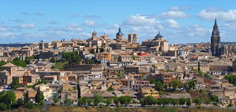 Panorama of Toledo with historical buildings and a cathedral under a blue sky with clouds, on the