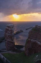 Red sandstone cliff with Lange Anna on the offshore island of Heligoland, mole as protection