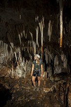 Young woman with helmet and headlamp, tourist between stalactites and stalagmites in a stalactite