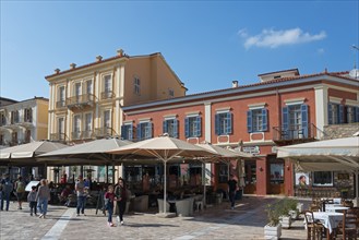 Historic city buildings with colourful facades and people strolling through a sunny city centre,