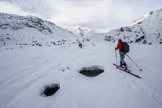 Ski tourers ascending in the rear Martell Valley, snow-covered mountain peak Monte Cevedale behind,