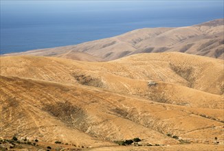 View of hills and sea in barren interior of Fuerteventura, Canary Islands, Spain, Europe