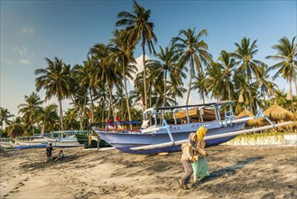 Muslim woman in the evening sun at Mangsit beach in Sengiggi, boat, fishing boat, palm beach,