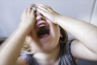 Symbolic photo on the subject of tantrums in children (staged scene) . A little girl holds her