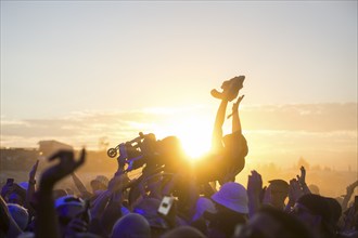 A wheelchair user crowdsurfing in front of sunset at the Highfield Festival on Friday, Störmthaler