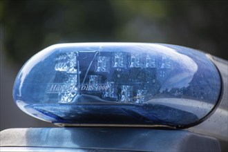 Symbolic image of a police operation: close-up of a flashing blue light on a police car