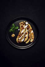 Fried eggplant slices, with white sauce, on a black background, top view, vertically, without