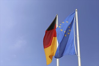 German and European flags against a blue sky