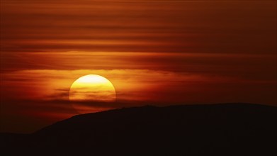 A fascinating sunset, where the setting sun bathes the sky in shades of red and disappears behind a