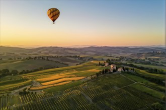 Hot air balloon drifting above undulating tuscan hills in sunsets golden light, AI generated