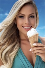 A blonde woman enjoys eating an ice cream in a cone