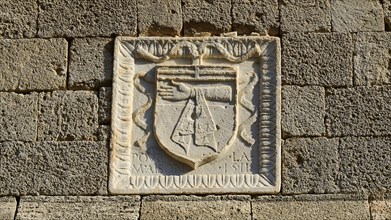 Square stone relief with a coat of arms showing an arm on a historic wall, Knights Street, Rhodes