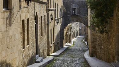 Historic, narrow street with stone buildings and an arch, deserted, Knights' Street, Rhodes Old