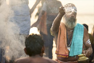 Hindu priest performing a fire ritual at Ghat Agni Theertham, Rameswaram or Rameshwaram, Pamban