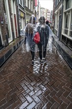 Tourists in rainy weather, with plastic ponchos, in the historic centre of Amsterdam, Netherlands