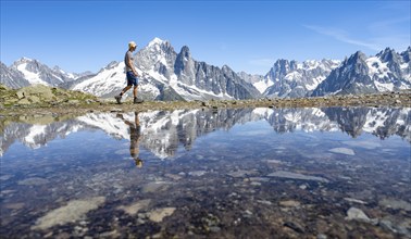 Tourist in front of mountain landscape, reflection in a small mountain lake, mountain peaks