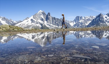 Tourist in front of mountain landscape, reflection in a small mountain lake, mountain peaks