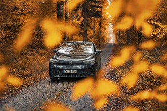 A car stands in an autumnal forest behind orange leaves, electric car, VW ID 5, Gechingen, Black