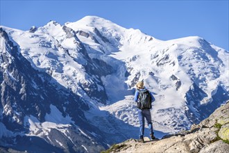 Mountaineer on a hiking trail in front of a mountain landscape, view of spectacular glaciated peaks