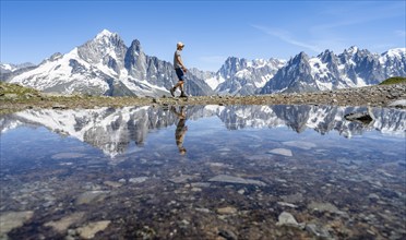 Mountaineer in front of a mountain landscape, reflection in a small mountain lake, mountain peaks