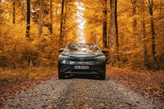 A car drives through the forest on an autumnal, leaf-lined road, electric car, VW ID 5, Gechingen,