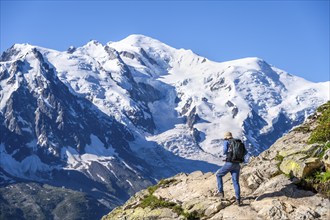 Mountaineer on a hiking trail in front of a mountain landscape, view of spectacular glaciated peaks