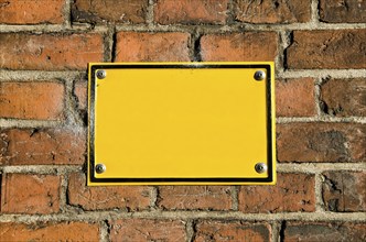 Blank yellow metal signboard on red brick wall