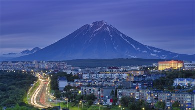 Panorama of night city of Petropavlovsk-Kamchatsky on background cone of volcano, urban development