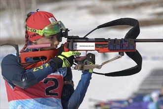 Sportswoman biathlete aiming, rifle shooting, reloads standing position. Biathlete Polina Yegorova