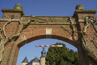 Monumental archway with climbing plants, behind it a historic castle, Borken, North