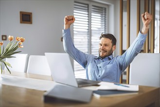 Excited caucasian man cheering for his team, watching a football game on his laptop, man