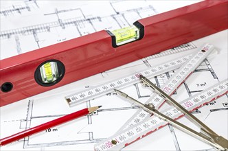 Spirit level, pencil, yardstick and compass calipers on a construction plan