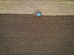 Aerial view of a tractor ploughing a field, a farmer in a modern tractor ploughing field on a sunny