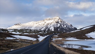 Typical Icelandic snowy nature mountain landscape and empty road near Arnarstapi area in