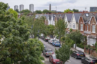 A residential street with parked cars and Victorian houses, lined with trees, Kew, London, England,