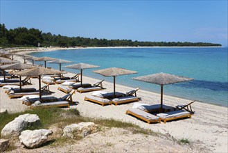 Quiet beach with parasols and sunbeds, crystal clear water and blue sky create a relaxed