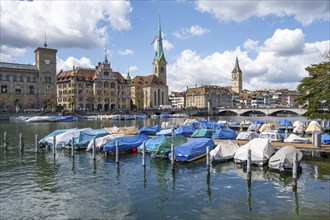 Boats at the jetty in the river Limmat, towers of Fraumünster and St Peter, Old Town, Zurich,