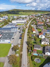 Aerial view of a railway track through a mixed residential and commercial area in autumn weather,