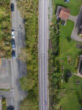 Aerial view of a railway track running through a green residential area and flanked by streets and