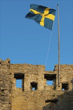 Old city wall with flag or banner of Sweden, former Hanseatic city of Visby, UNESCO World Heritage