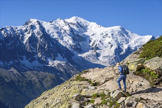 Mountaineer on a hiking trail in front of a mountain landscape, view of spectacular glaciated peaks