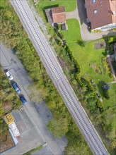 Aerial view of a railway track through a residential area with neighbouring streets and gardens,