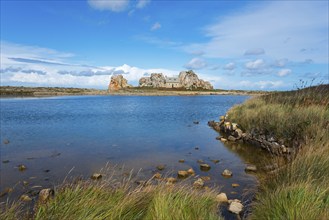 A house stands between rocks on a lake under a blue sky with clouds, House between the rocks on the