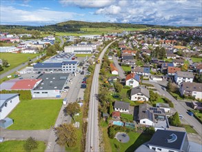 Aerial view of an industrial and residential area with a railway track running through it, tamping