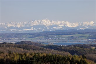 A wide landscape with a lake and snow-capped mountains of Säntis in the Alpstein in the background