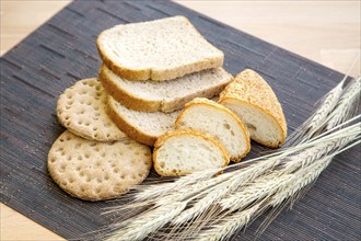 Various sliced bread and wheat on a table, still-life