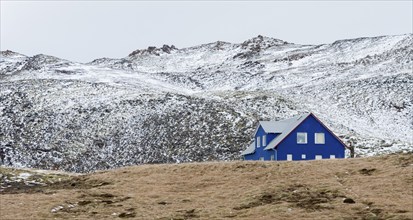 Icelandic landscape with blue chalet farm house in Reykjanes peninsula, Mountains covered in snow