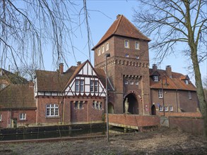 Historic building on a canal with half-timbering and brick tower, coesfeld, münsterland, germany